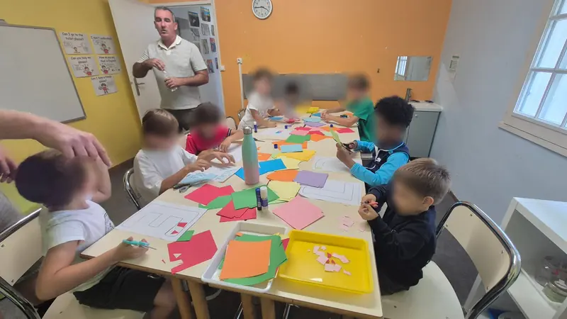 Atelier de découpage et de collage de papiers de couleur, avec un enseignant