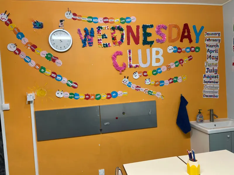 The Wednesday Club room: an orange wall decorated by the children, with numbers and months in English