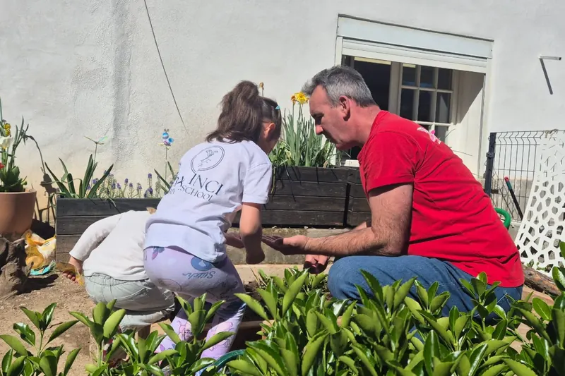Deux enfants et un adulte plantent dans les jardinières de la cour de l'école